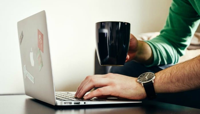 Man using laptop while holding a black cup