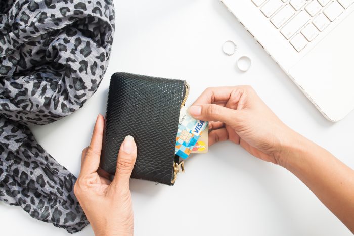 Hands holding credit cards and using laptop.