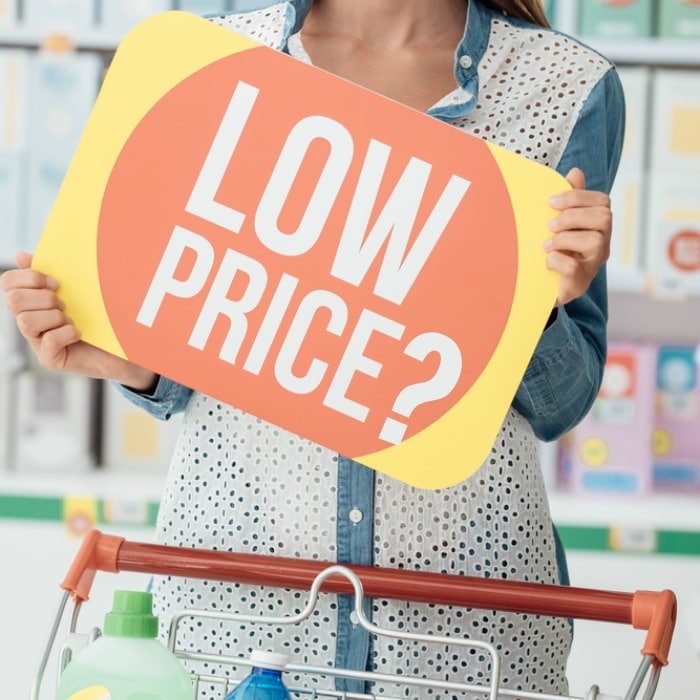 Smiling woman shopping at the supermarket and holding a discount sign