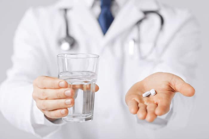 picture of doctor hands giving white pills and glass of water