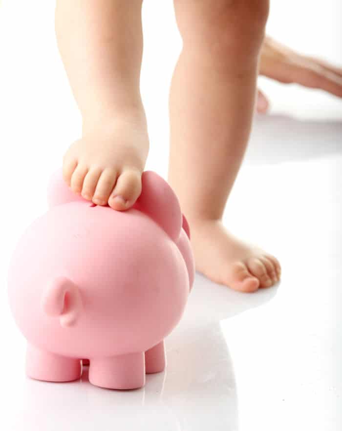 Baby legs on piggy bank - isolated