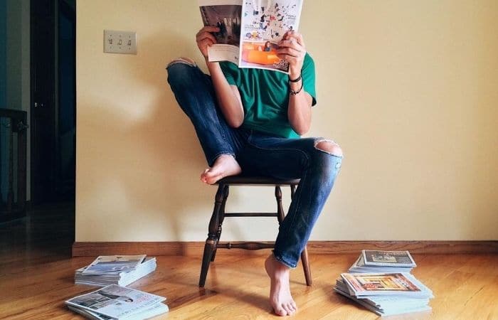 man reading magazines on a chair