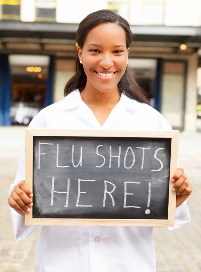 pharmacist holding a flu jab sign