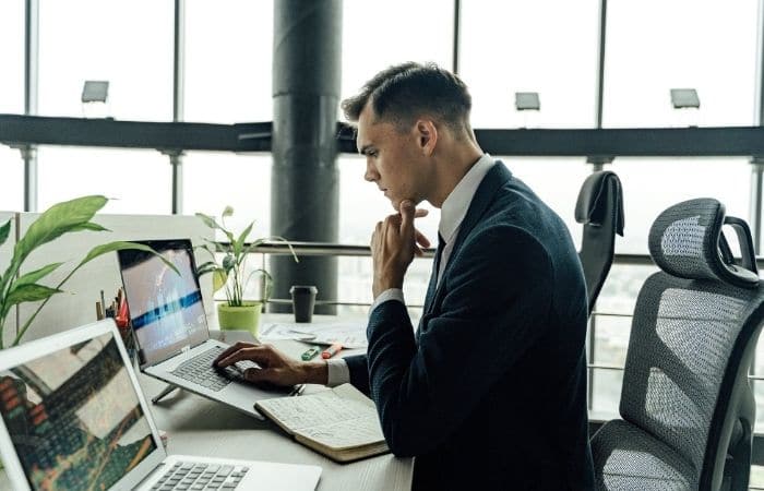 man in black suit jacket using macbook pro