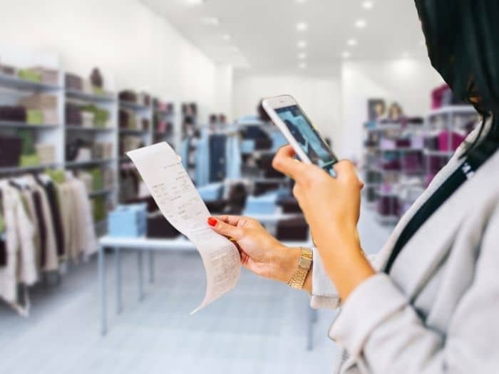 woman taking a photo of a receipt in a clothing shop