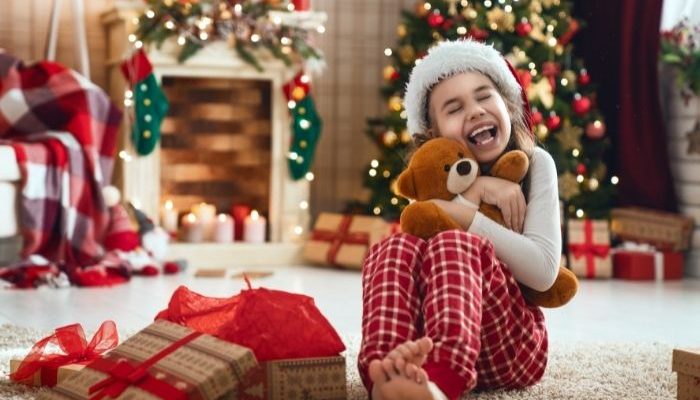 overwhelmed kid sitting in front of presents under the tree