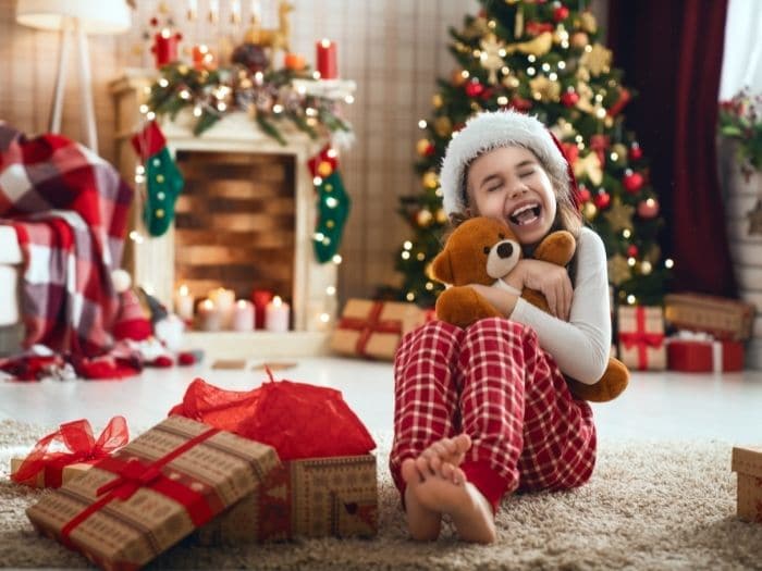 overwhelmed kid sitting in front of presents under the tree