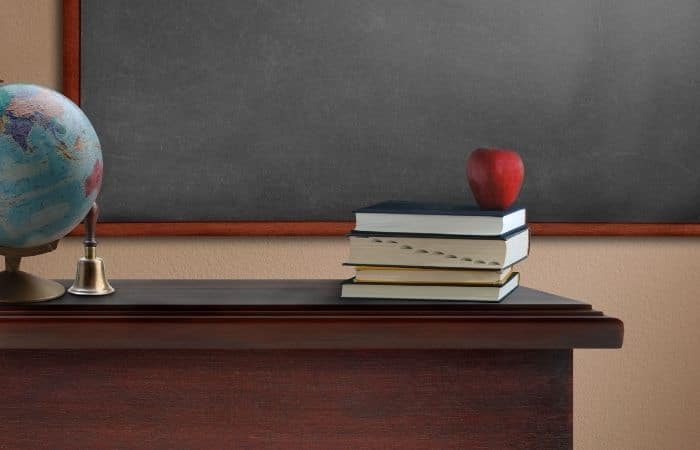 apple on books in front of blackboard