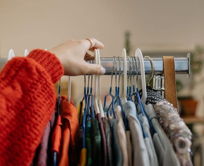 hand picking coat hanger from clothing rack