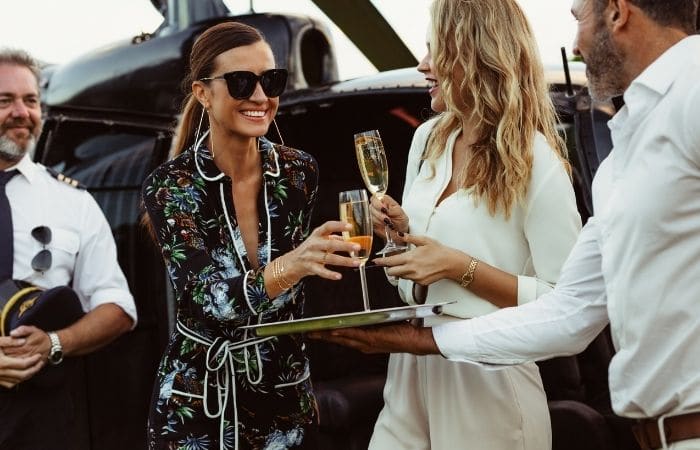 women being presented with champagne from man in uniform