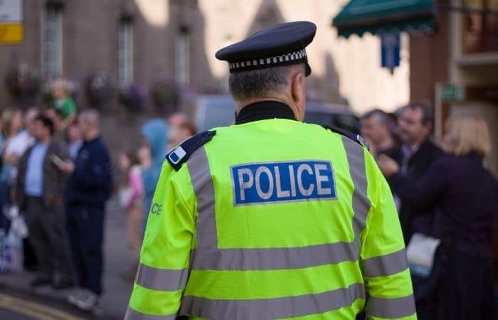 police officer in a high viz jacket facing a crowd of people