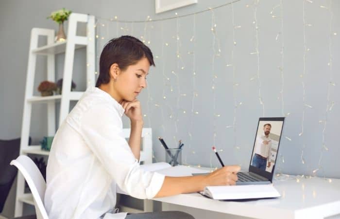 woman working from home at a desk with fairy lights hanging in front of her on the wall.