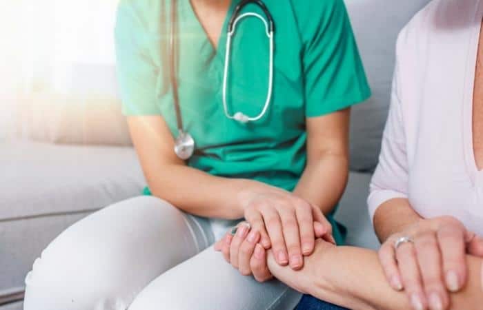 caregiver holding the hand of a senior person