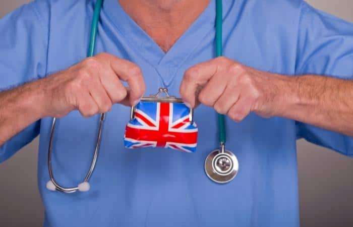 doctor in scrubs with aa stethescope holding a union jack purse