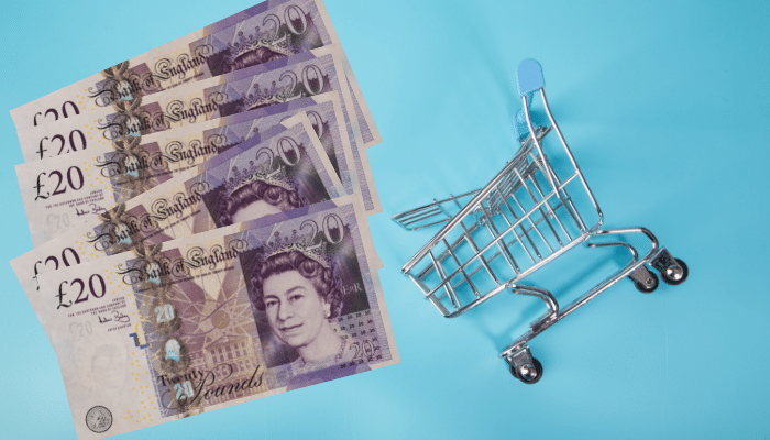 £20 notes next to a small shopping trolley, on a blue background