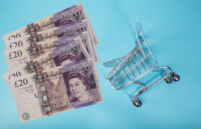 £20 notes next to a small shopping trolley, on a blue background