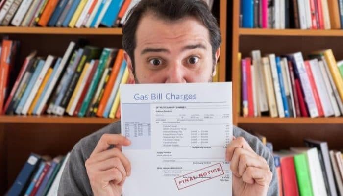 man with surprised look hiding behind final notice gas bill