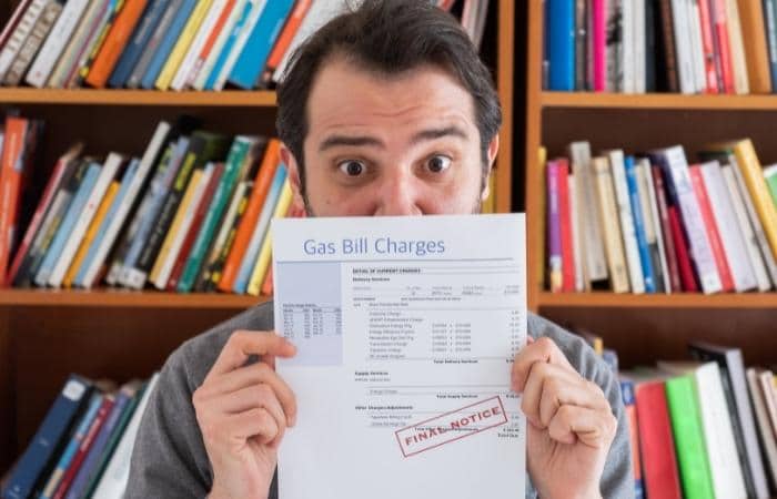 man with surprised look hiding behind final notice gas bill