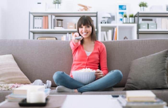 woman on sofa changing channel