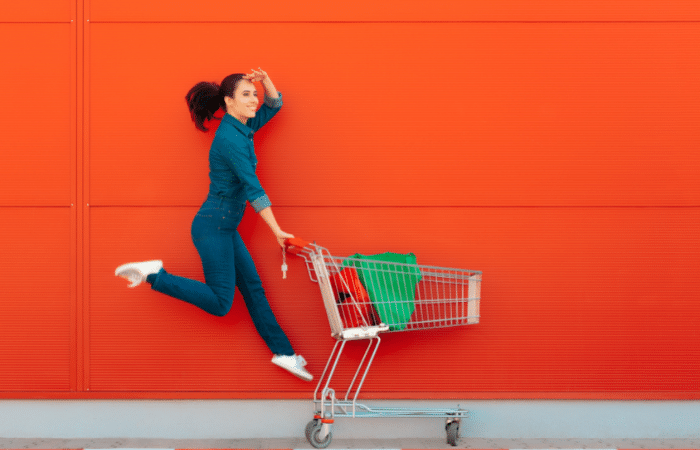 woman jumping and holding onto trolley in front of a red background