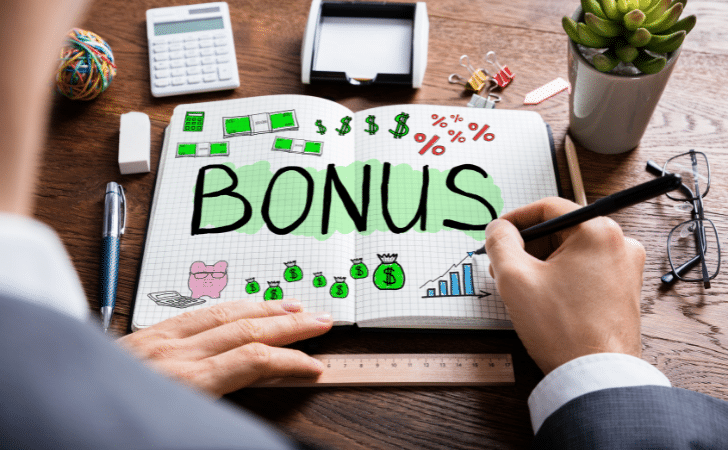 man doodling the word bonus and money symbols in a note book