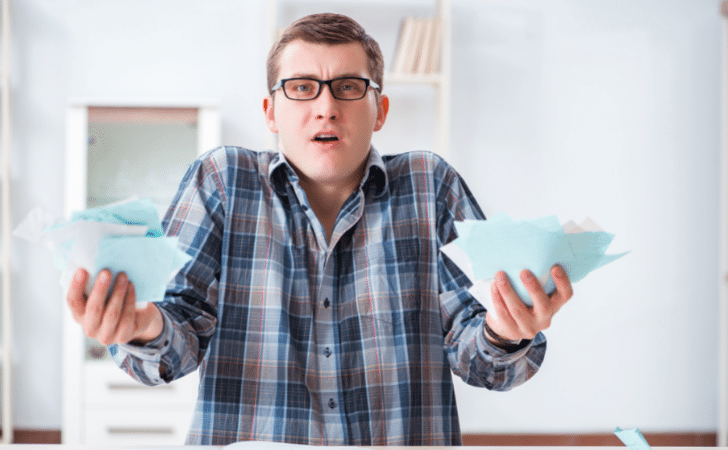 confused man holding pieces of green paper