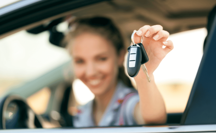 woman holding car keys while sat in the driver's seat of a car