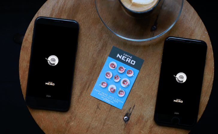 overhead view of two phones on a wooden table with a stamped Caffe Nero loyalty card