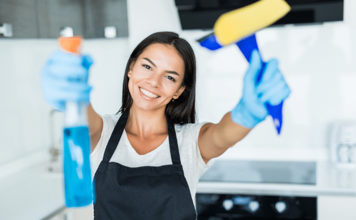 smiling domestic cleaner holding cleaning products