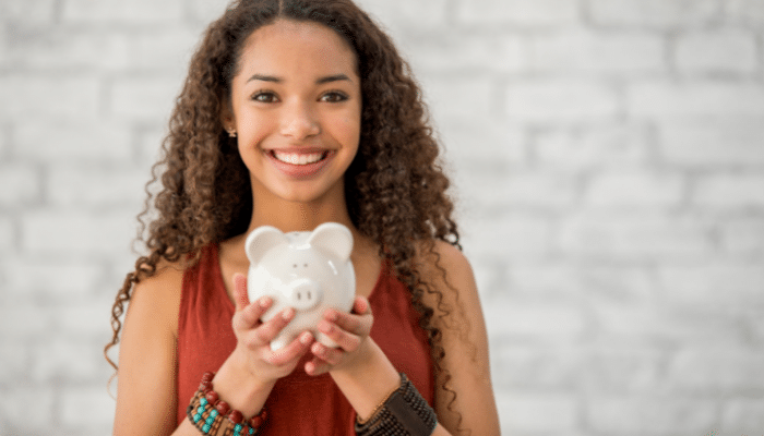 teenage girl smiling and holding a white piggy bank