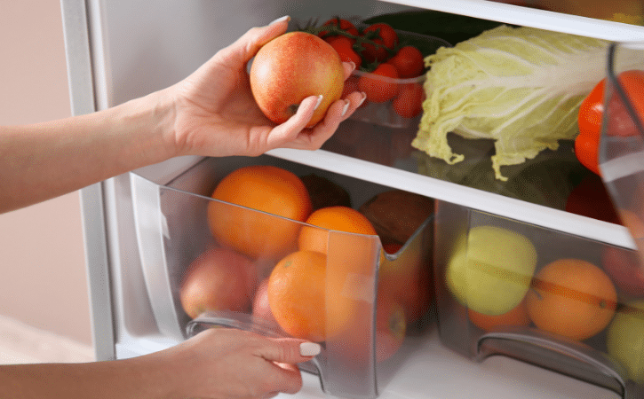 hand picking an apple from the fridge