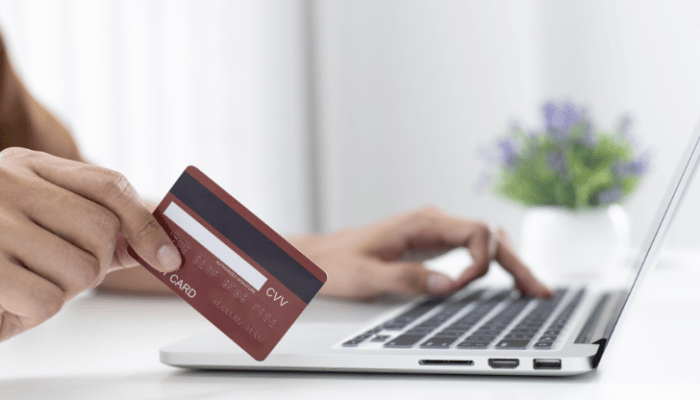 holding credit card next to laptop