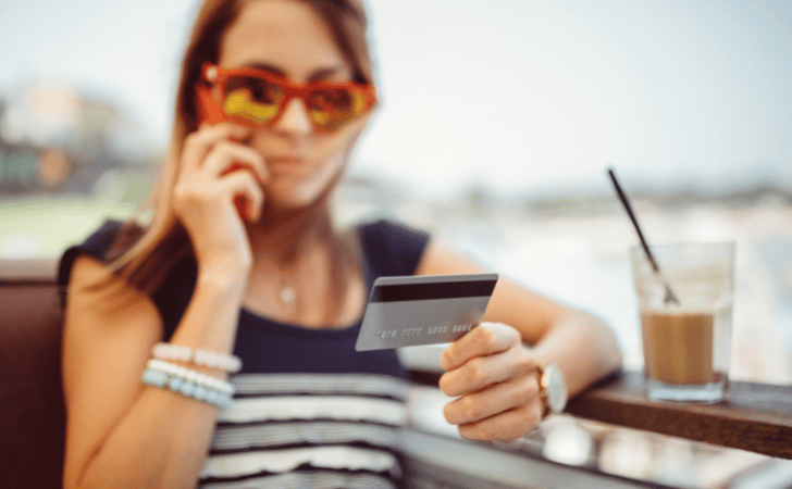 woman talking on the phone with a credit card in her hand