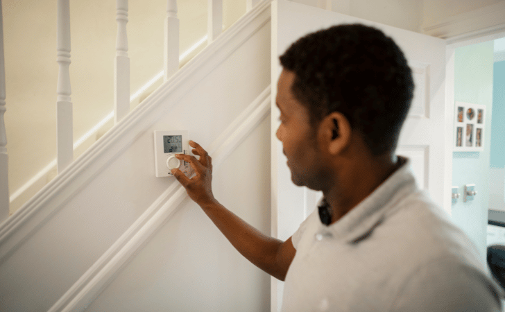 man turning down thermostat