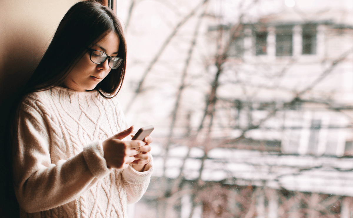 sad girl texting at window