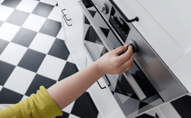 woman adjusting dial of oven