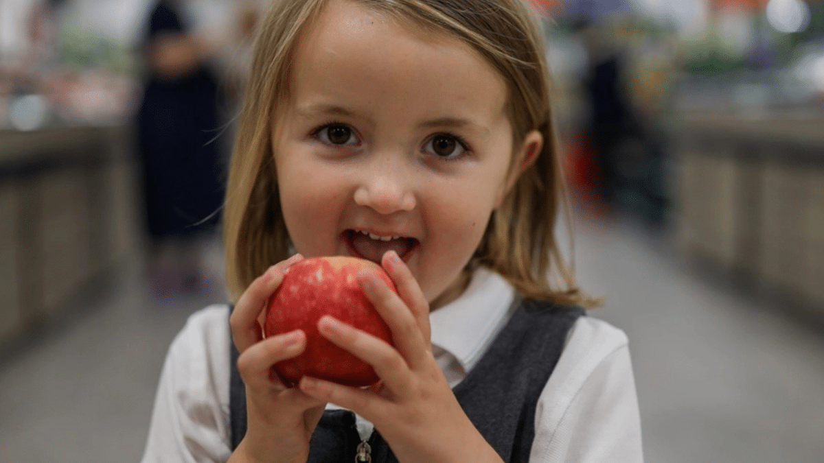 young girl holding an apple in her hands about to eat it