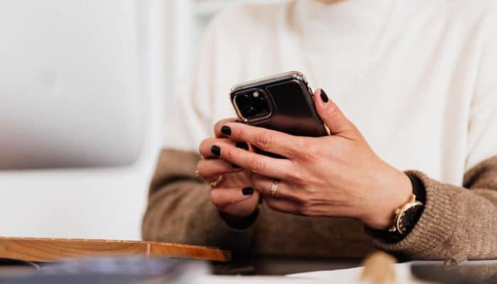 Person using a mobile phone at home while checking their network deal
