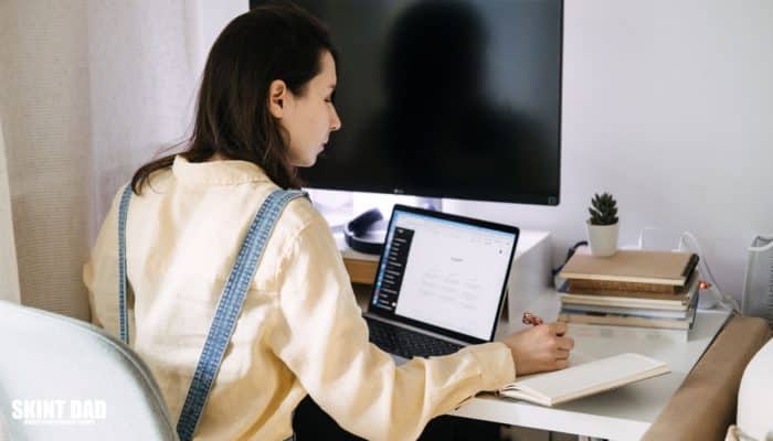 Woman working on a laptop at home office with notebook and AI tool ChatGPT