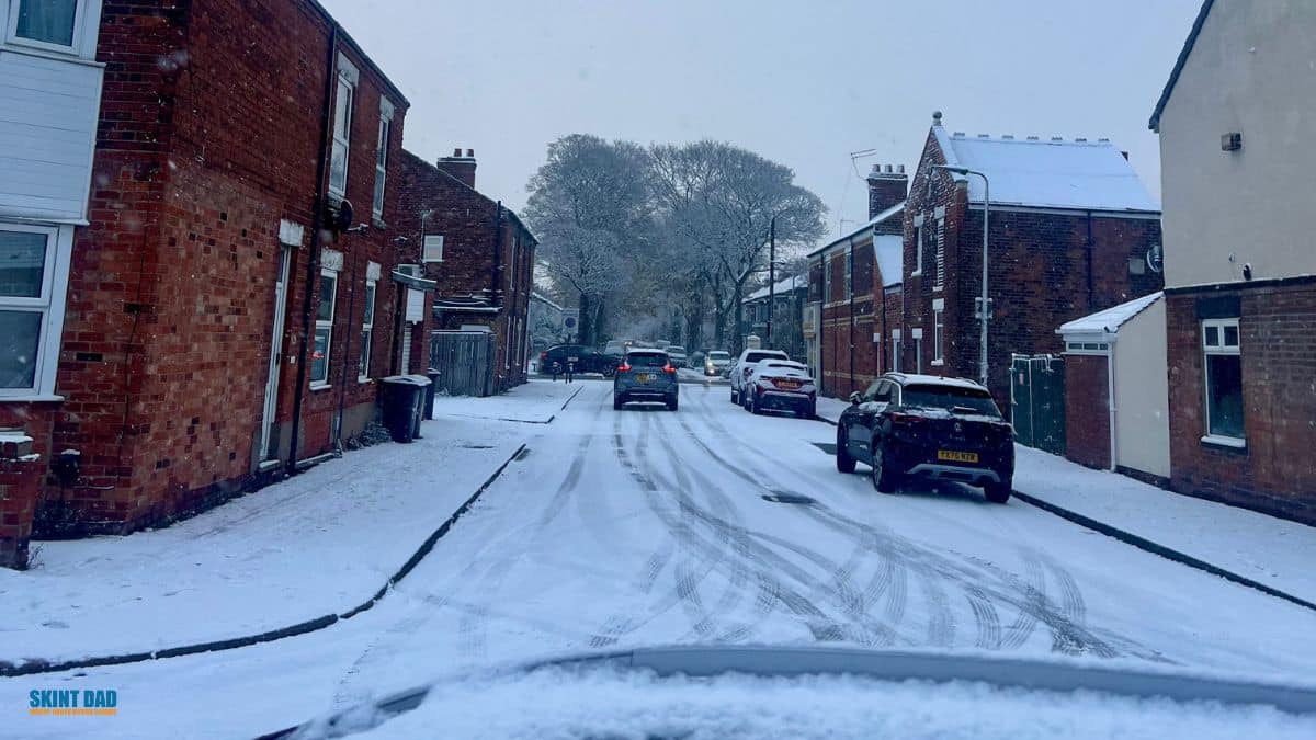 UK residential street covered in snow, showing freezing weather conditions linked to Cold Weather Payments.