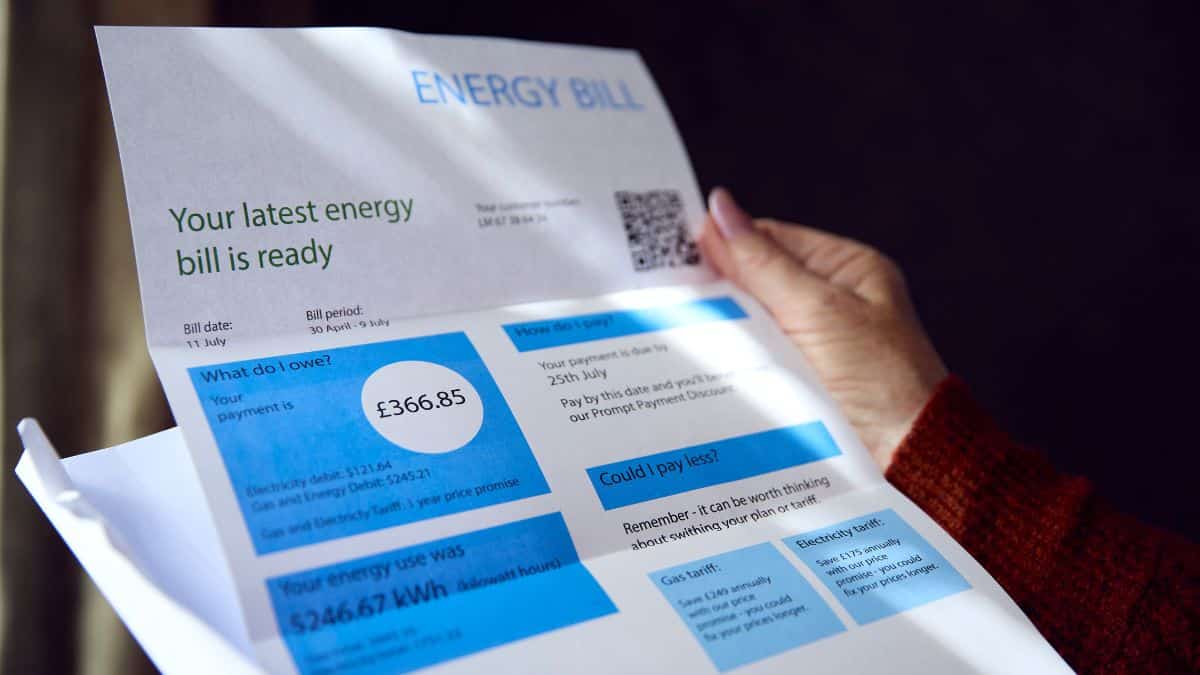 Person in a British home looking worried while checking an energy bill on their phone.