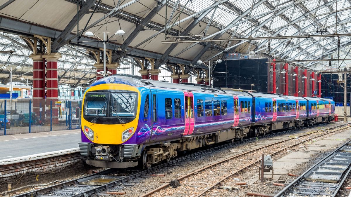 Commuter tapping a train ticket at a station barrier during the 2025 rail fare freeze in England
