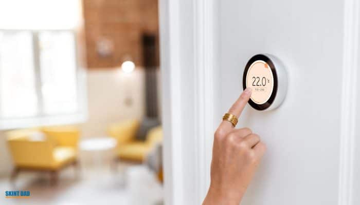 Hand turning a smart thermostat up by one click to reflect the small January Ofgem price cap increase.