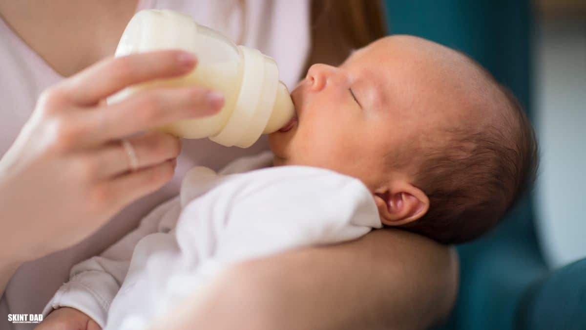A parent bottle feeding a baby at home, used to illustrate new UK rules allowing loyalty points to be used on infant formula.