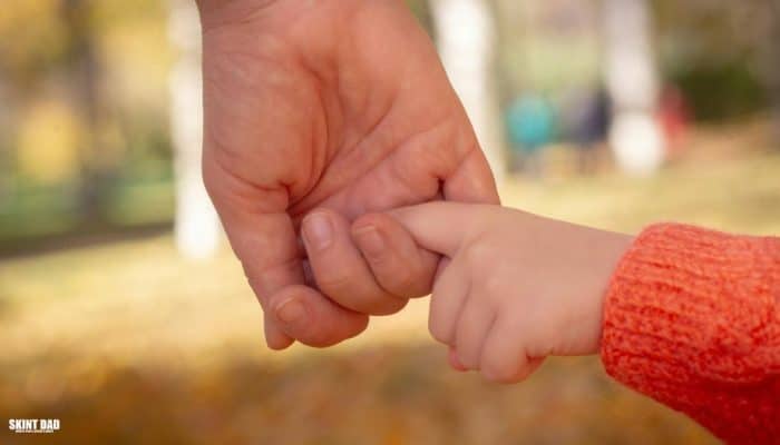 Child holding a parent’s hand, showing the support families need as new child poverty plans are introduced in the UK.