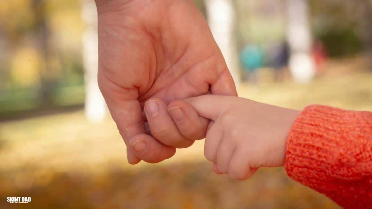 Child holding a parent’s hand, showing the support families need as new child poverty plans are introduced in the UK.
