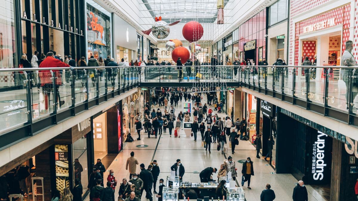 Busy UK shopping centre decorated for Christmas with crowds walking through the mall.