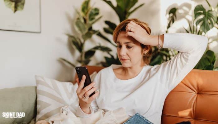 Checking a UK bank statement on a phone to spot forgotten subscriptions.