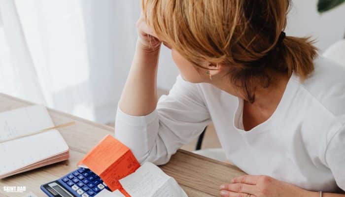 A lady trying to deal with a pile of household bills and letters on a table.
