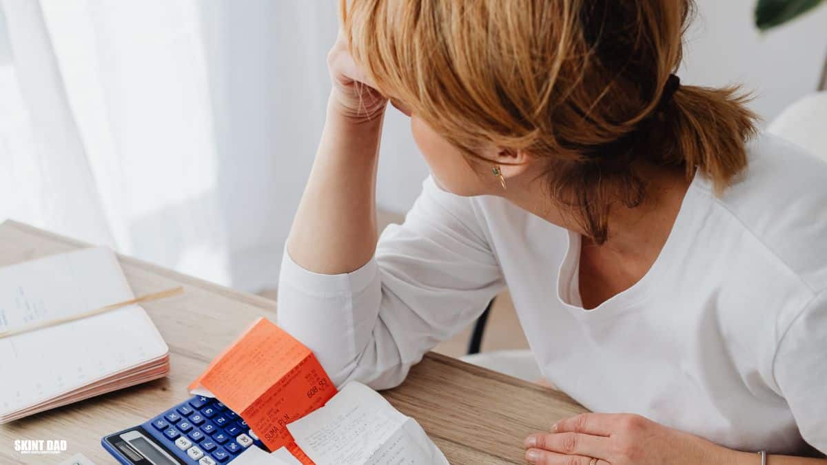 A lady trying to deal with a pile of household bills and letters on a table.